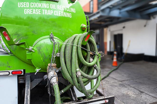 a technician pumping a grease trap in a commercial building in Aldan